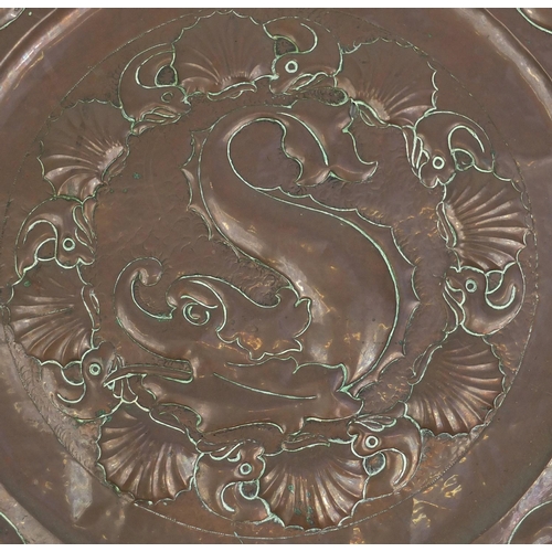 609 - Large Arts & Crafts copper charger embossed with stylised dolphins, 64cm in diameter