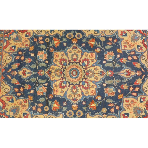 2025 - Rectangular Persian rug having a central flower head design surrounded by vines, onto and red and bl... 