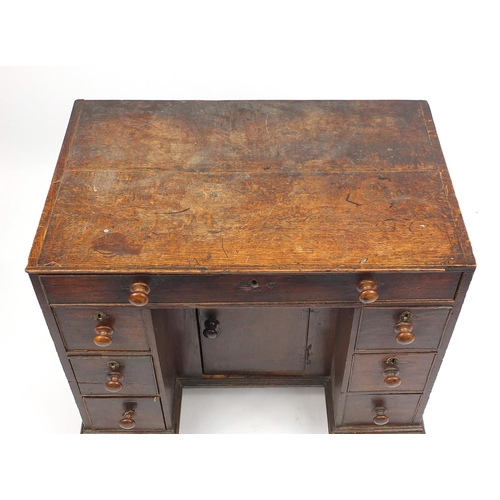 30 - Antique oak knee hole desk fitted with seven drawers, 76cm H x 83cm W x 52cm D