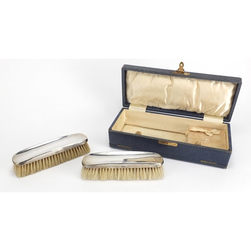 530 - Pair of silver backed clothes brushes, Chester hallmarked, with fitted case, 16cm in length