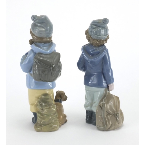 649 - Two Nao figures of a young boy and girl with winter clothing, the largest 20cm high