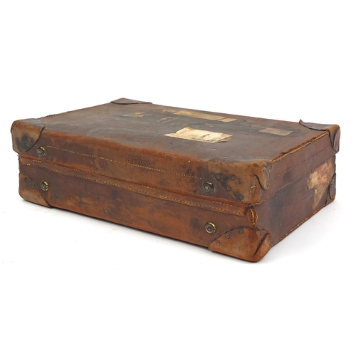 83 - Vintage brown leather suitcase, with some paper shipping labels, 62cm in length