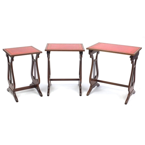 115 - Nest of three mahogany occasional tables with tooled leather tops and lyre supports, the largest 55c... 