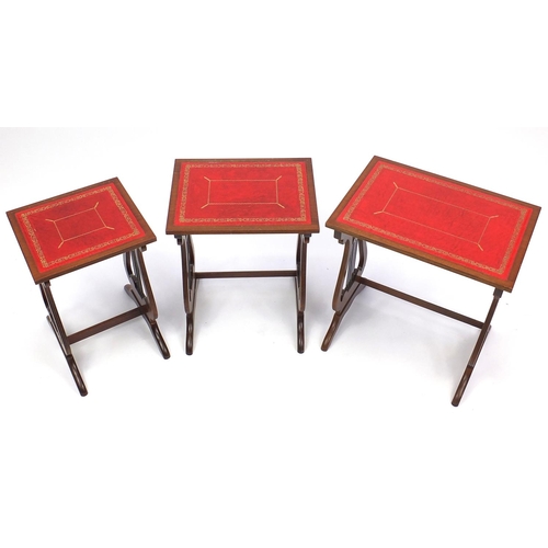 115 - Nest of three mahogany occasional tables with tooled leather tops and lyre supports, the largest 55c... 