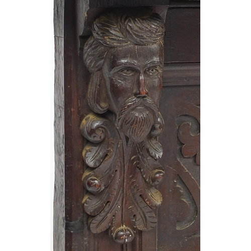 84 - Carved oak over mantel panel, with shelf support by two carved face masks, 90cm high x 145cm wide