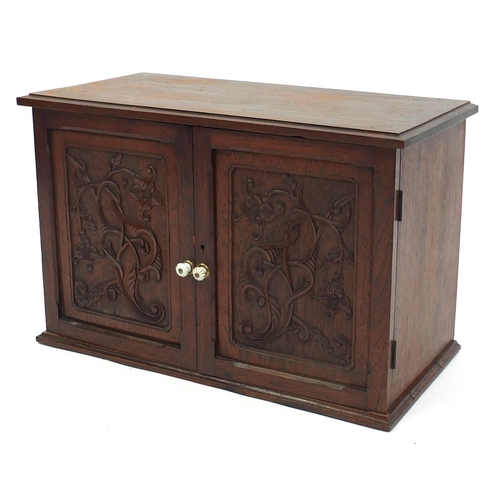 2056 - Walnut collectors cabinet, with a pair of cupboard doors carved with flowers enclosing seven drawers... 