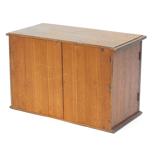2056 - Walnut collectors cabinet, with a pair of cupboard doors carved with flowers enclosing seven drawers... 