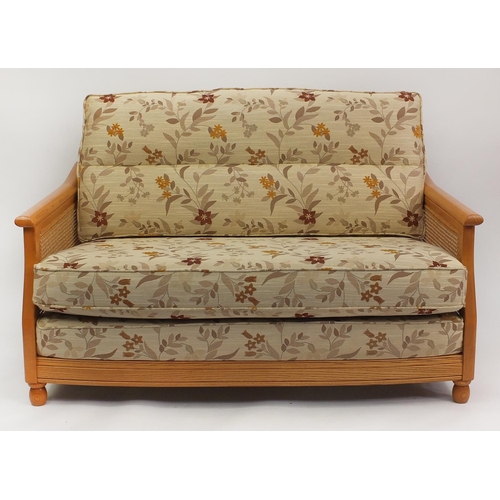 2012 - Ercol light elm bergere two seater settee with floral cushions, 95cm H x 137cm W x 104cm D (OPTION)