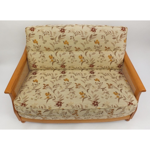 2012 - Ercol light elm bergere two seater settee with floral cushions, 95cm H x 137cm W x 104cm D (OPTION)