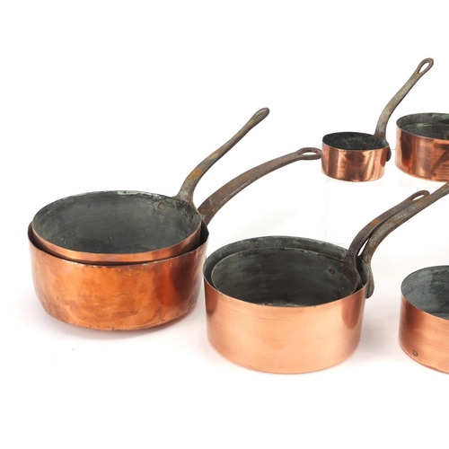 2174 - Graduated set of eight cast iron and copper saucepans, the largest 44cm in length