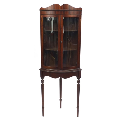 2028 - Mahogany bow fronted standing corner cabinet, raised on tapering fluted legs, 165cm high