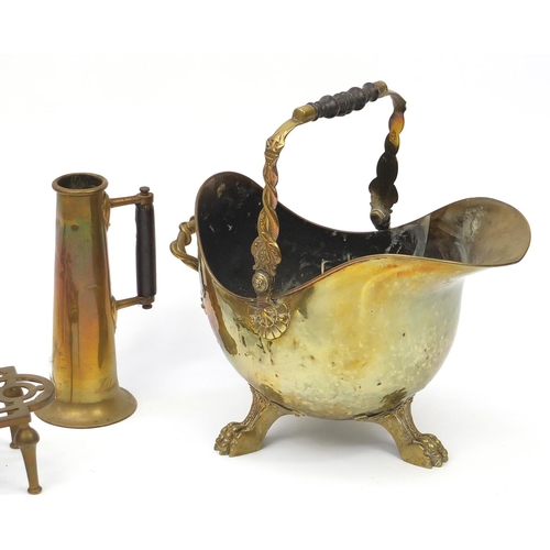 199 - Brass items, helmet shaped fire bucket with paw feet, two trivets and an Arts & Crafts flagon