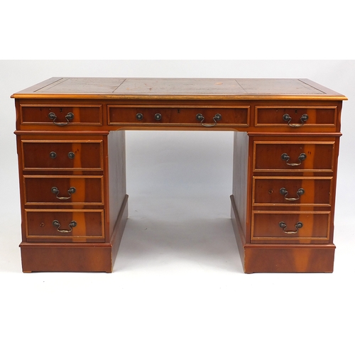 21 - Yew twin pedestal desk with tooled leather top, fitted with a series of drawers, 78cm H x 138cm W x ... 