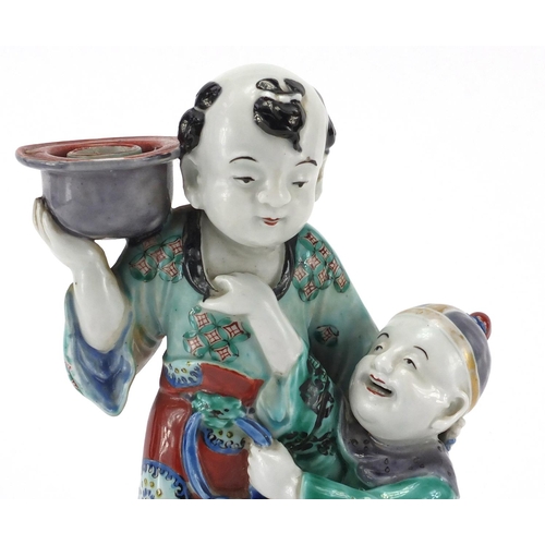 642 - Chinese porcelain figural candlestick, modelled as a father and child, hand painted in the famille v... 