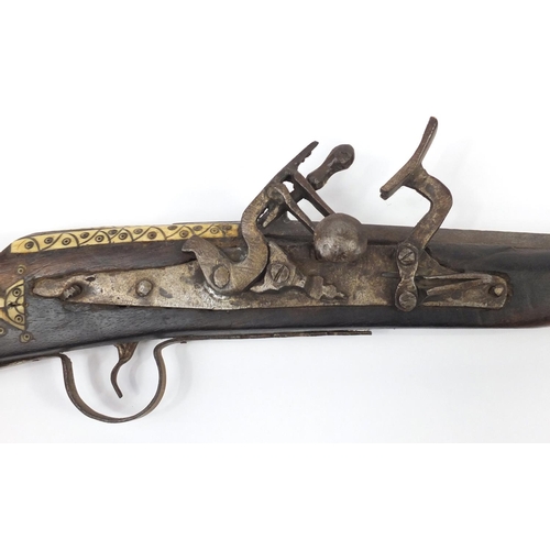 583 - Indian flint lock rifle with bone inlay and a similar pistol, the largest 160cm in length