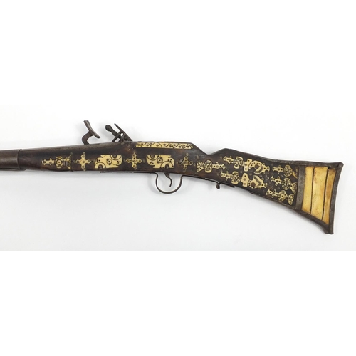 583 - Indian flint lock rifle with bone inlay and a similar pistol, the largest 160cm in length