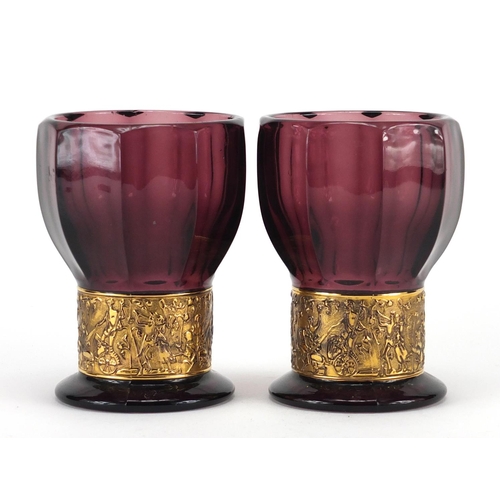 930 - Pair of Mosser purple glass goblet vases, each with a gilded band depicting Grecian warriors, indist... 