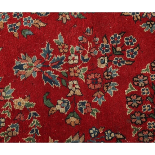 2041 - Rectangular Persian rug having an all over floral design within corresponding borders onto a red gro... 