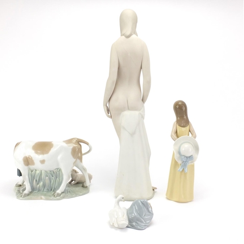 753 - Four pieces of Lladro including a group of a cow and piglet and large standing nude female, the larg... 