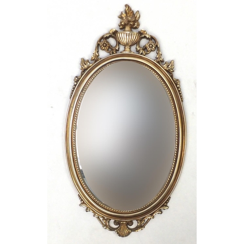10 - Oval gilt framed mirror with urn finial, 78cm x 41cm