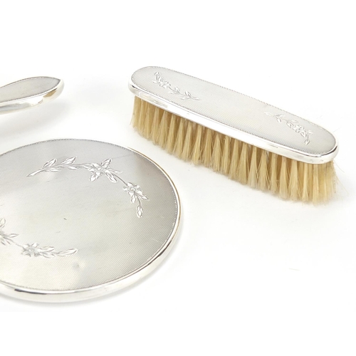 367 - Three silver backed vanity items, with engine turned decoration, hand mirror, hair brush and clothes... 