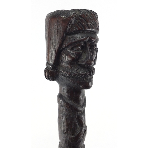 179 - Swiss black forest walking stick with figural carved  pommel, the shaft carved with berries and foli... 