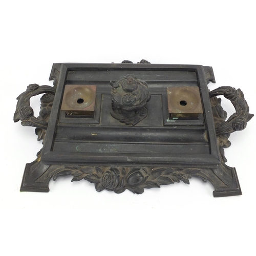 180 - Victorian cast iron desk stand, with twin handles and a pair of brass inkwells, 39cm wide