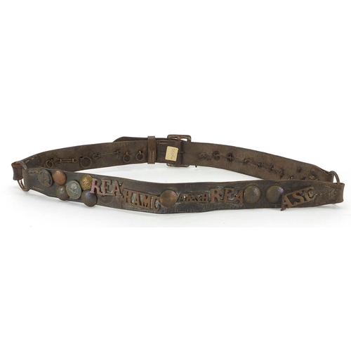 889 - Military interest brown leather belt, with a selection of badges and buttons including RFA