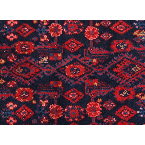 107 - Rectangular Hamadan rug having an all over stylised floral design within two borders onto a red grou... 