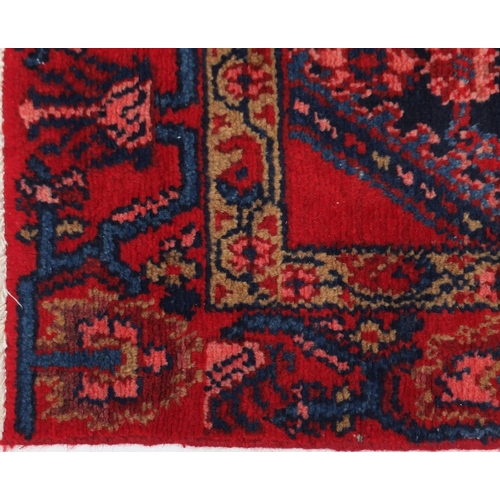 107 - Rectangular Hamadan rug having an all over stylised floral design within two borders onto a red grou... 