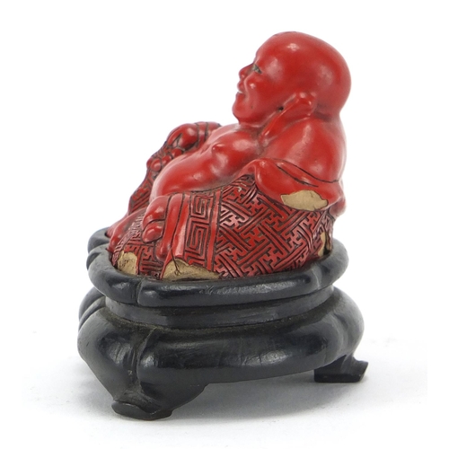 543 - Chinese Cinnabar lacquer figure of Buddha, raised on a hardwood stand, overall 7.5cm high