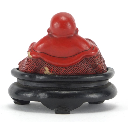 543 - Chinese Cinnabar lacquer figure of Buddha, raised on a hardwood stand, overall 7.5cm high