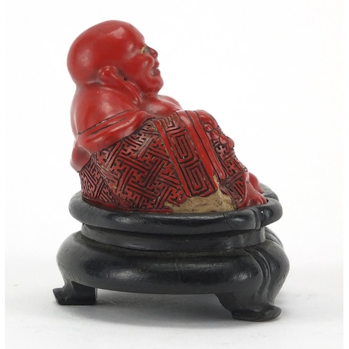 543 - Chinese Cinnabar lacquer figure of Buddha, raised on a hardwood stand, overall 7.5cm high