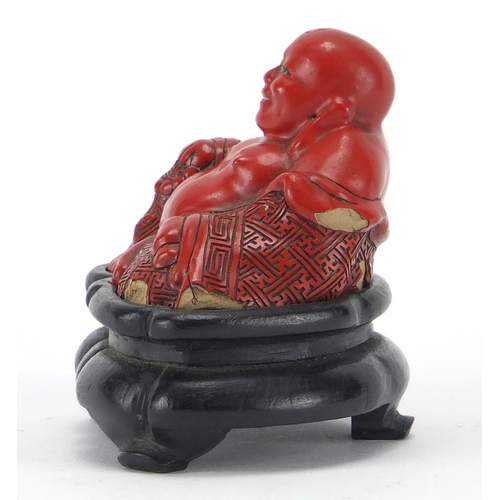 543 - Chinese Cinnabar lacquer figure of Buddha, raised on a hardwood stand, overall 7.5cm high