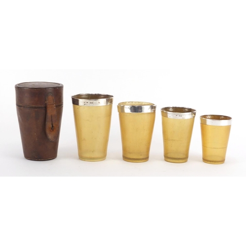 42 - Graduated set of four 19th century horn travelling beakers with silver rims, housed in a tan leather... 