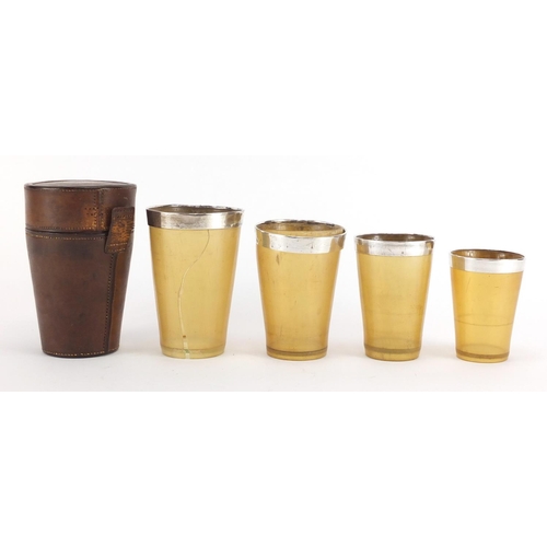 42 - Graduated set of four 19th century horn travelling beakers with silver rims, housed in a tan leather... 