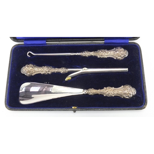 2551 - Silver handled glove stretchers, button hook and shoe horn, housed in a velvet lined tooled leather ... 