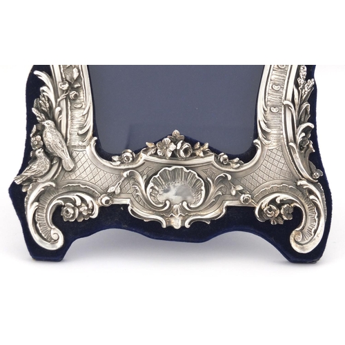 2534 - Modern silver easel photo frame, relief decorated with cupids and birds amongst flowers, 31cm high