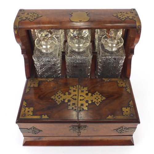 67 - Victorian walnut three bottle Tantalus with brass mounts, fitted interior and base drawer housing tw... 