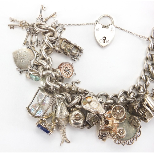 2781 - Heavy silver charm bracelet, with a large selection of mostly silver charms including steam locomoti... 