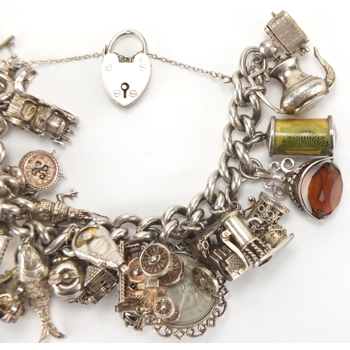 2781 - Heavy silver charm bracelet, with a large selection of mostly silver charms including steam locomoti... 