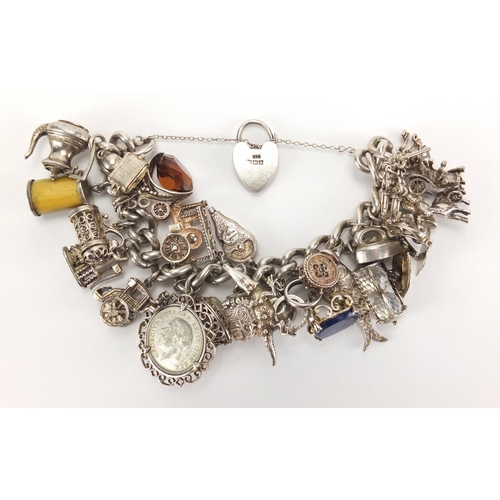 2781 - Heavy silver charm bracelet, with a large selection of mostly silver charms including steam locomoti... 