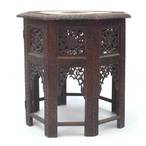 2076 - Indian hardwood octagonal folding table profusely carved and pierced with flowers, 56.5cm high x 55c... 