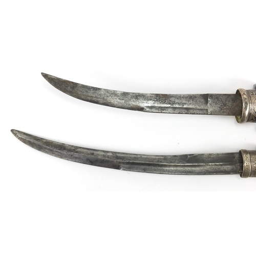 588 - Two Islamic daggers with brass sheaths having silver inlay, engraved with stylised scrolls, the larg... 