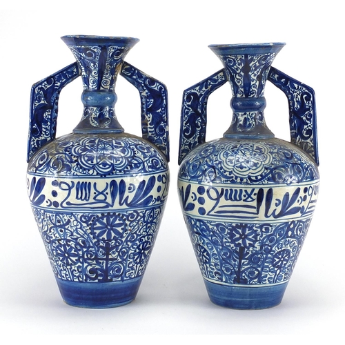 596 - Pair of Middle Eastern pottery vases, each with twin handles, both hand painted with script and flow... 