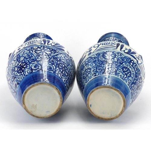 596 - Pair of Middle Eastern pottery vases, each with twin handles, both hand painted with script and flow... 