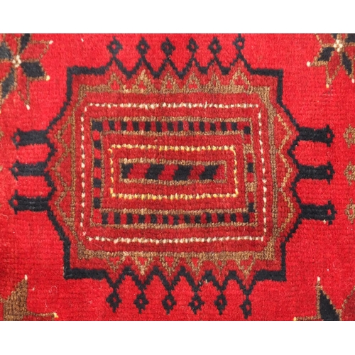 10 - Red ground rug with all over geometric design, 210cm x 108cm