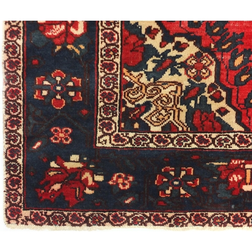 30 - Rectangular Persian rug, with all over floral design onto a predominantly blue and red ground, 200cm... 