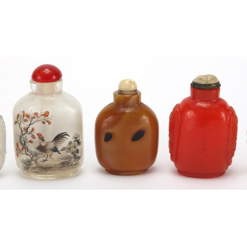 689 - Seven Chinese hardstone and glass snuff bottles together with a group of stoppers, including reverse... 