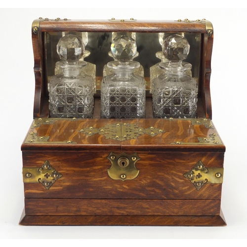 110 - Victorian oak three bottle tantalus with Bramah lock, brass mounts, fitted interior and base drawer ... 